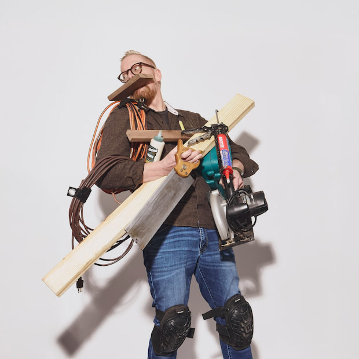 Derek Stulpin carrying a stack of DIY tools and lumber, showing his woodworking hobby
