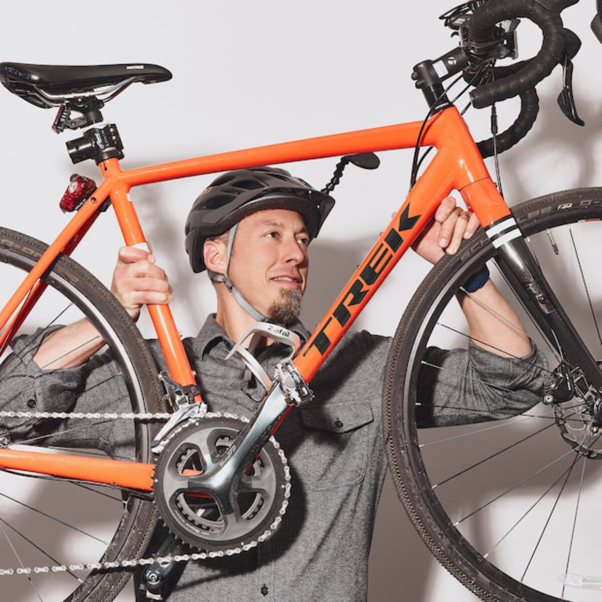 Karl Bear lifting an orange road bike while geared up with a helmet
