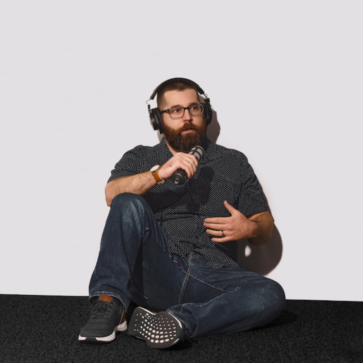 Zechariah Eshack recording a podcast with headphones and a handheld mic